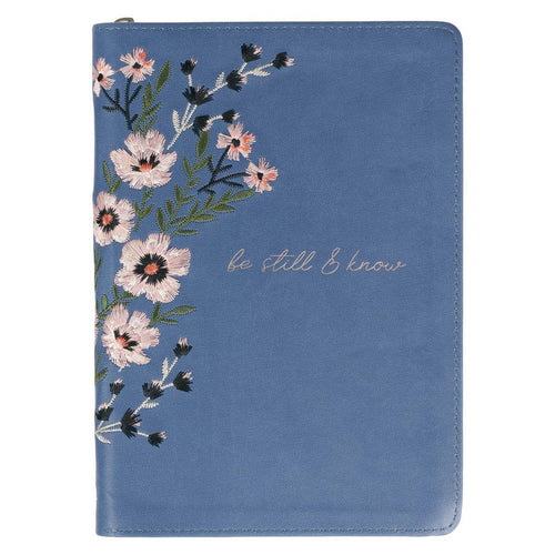 Blue notebook journal with floral design and 'be still & know' text on a white background