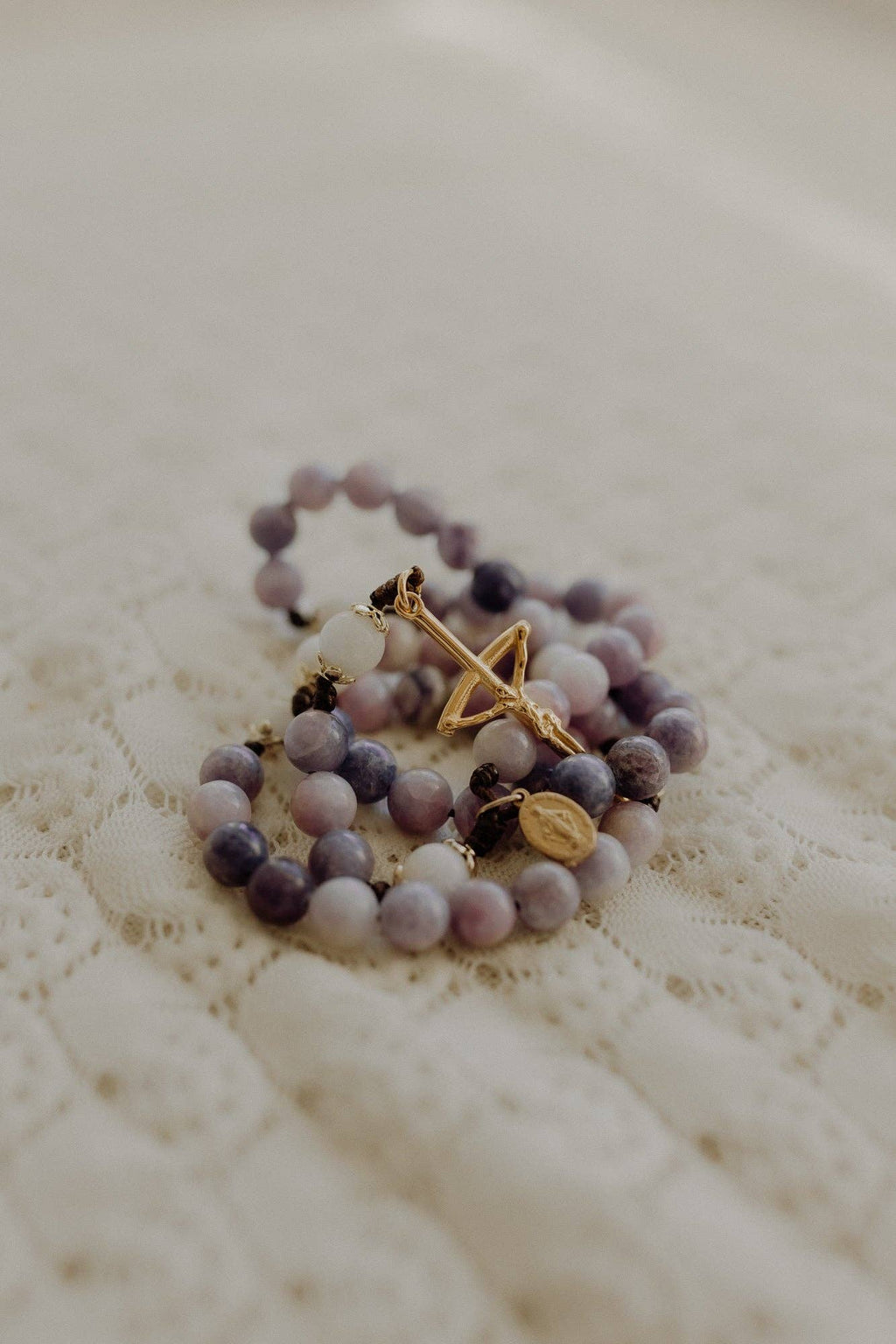 Purple and white beaded rosary with a gold cross pendant 