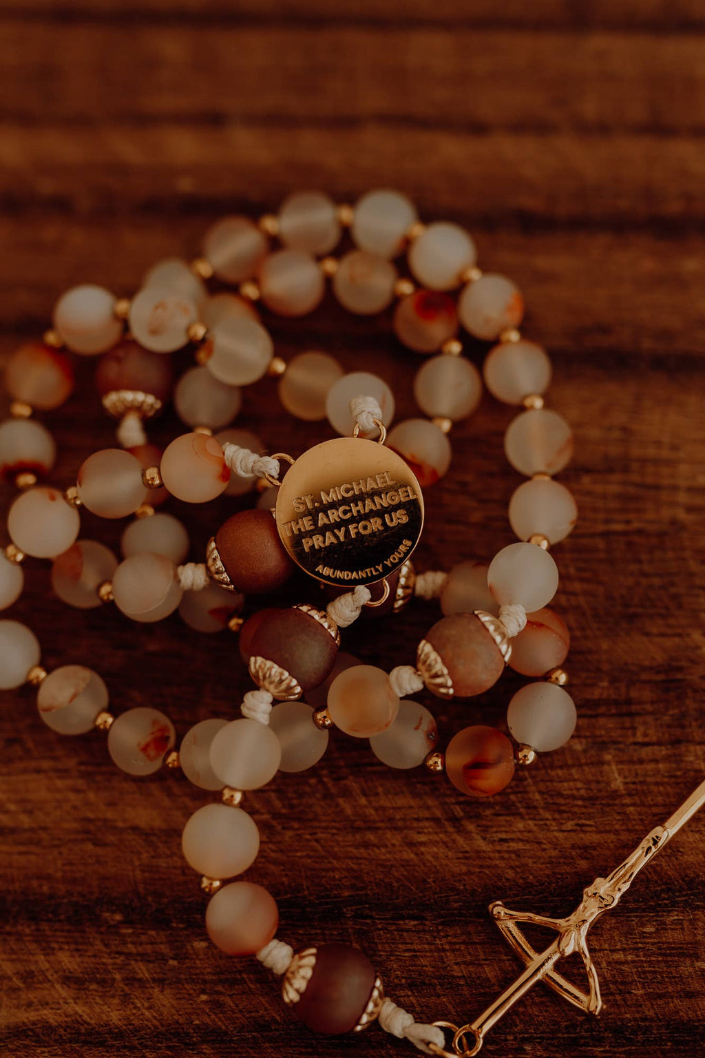 Rosary with Saint Michael medal on a wooden surface