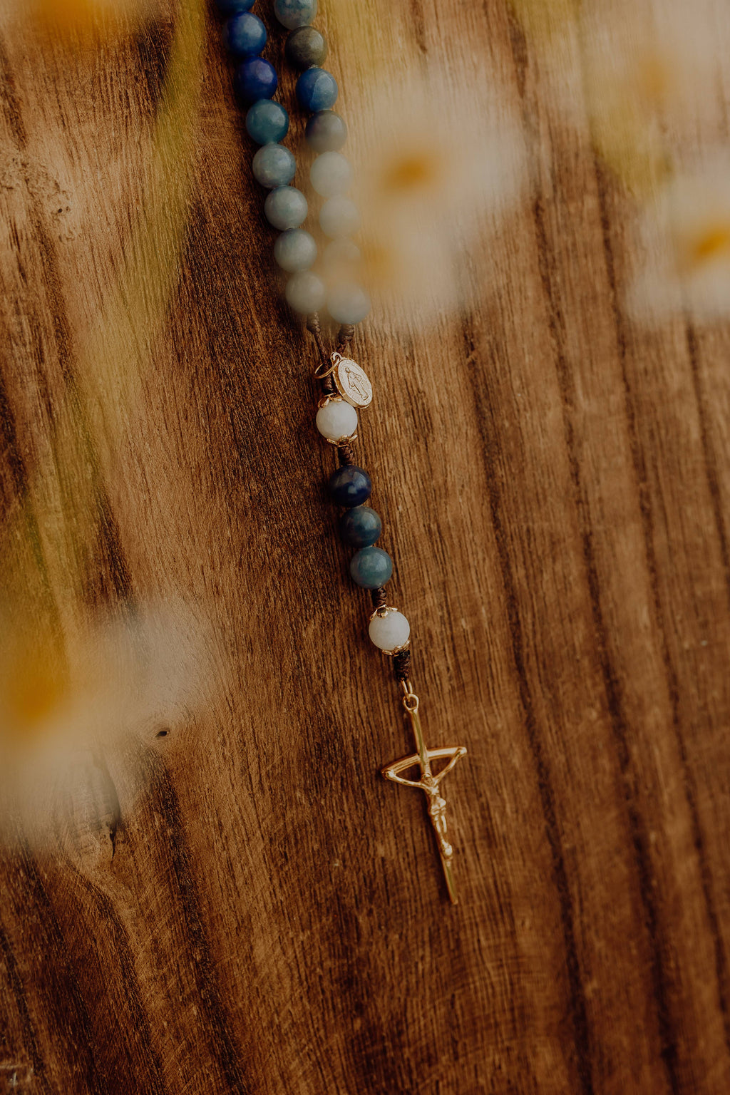 Beaded rosary with a gold pendant crucifix on a wooden surface