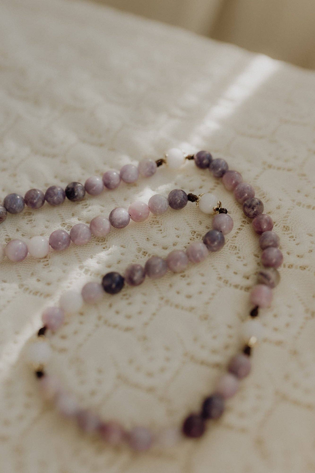 Rosary with purple and white beads on a textured surface