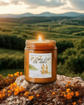 Candle in a jar with a label on a rock in a scenic outdoor setting