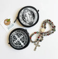 Two round black St. Benedict Medal Rosary Pouch with white designs and a rosary on a white background.