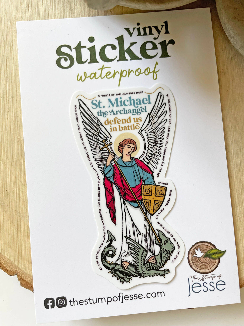 A die-cut vinyl sticker of St. Michael the Archangel is displayed on its white backing card, which features text indicating it is waterproof.