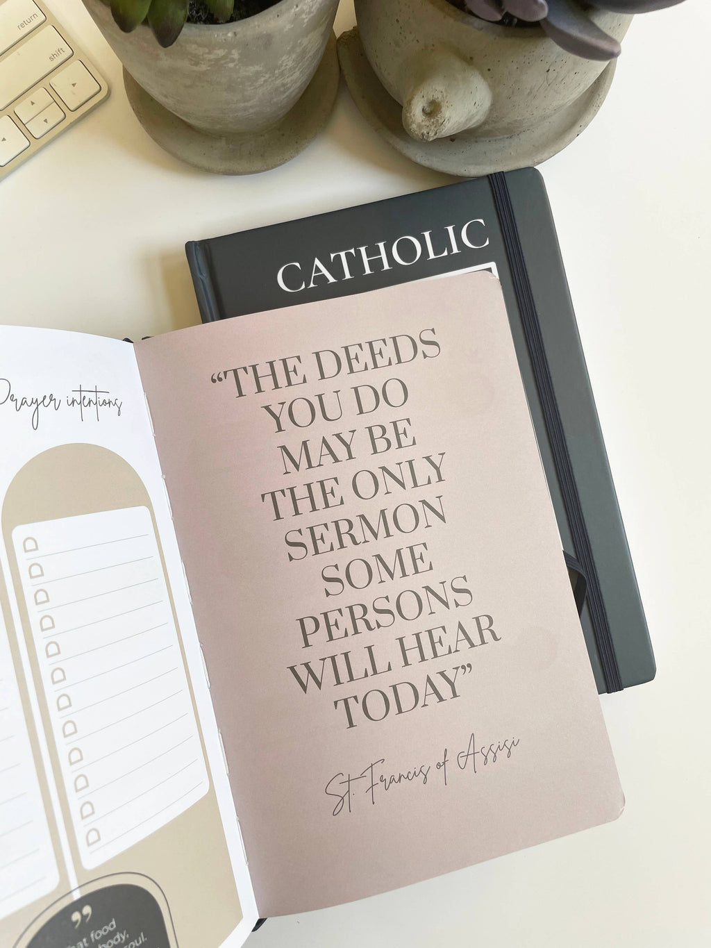 Notebook with inspirational quote on a desk with plants and keyboard