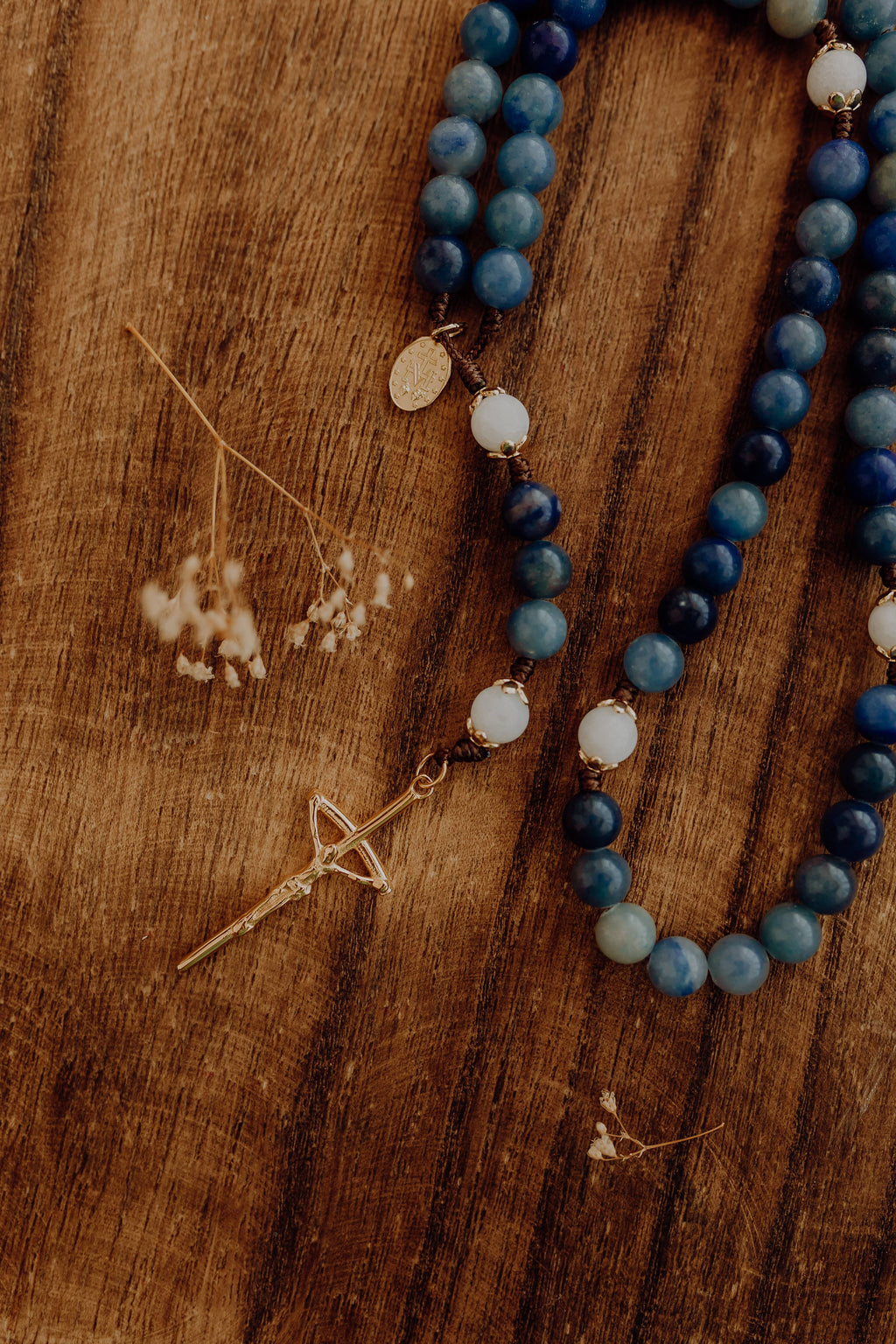 Blue beaded rosary with gold accents on a wooden surface
