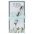 Notebook with floral design and pen set, tied with a ribbon, on a white background.