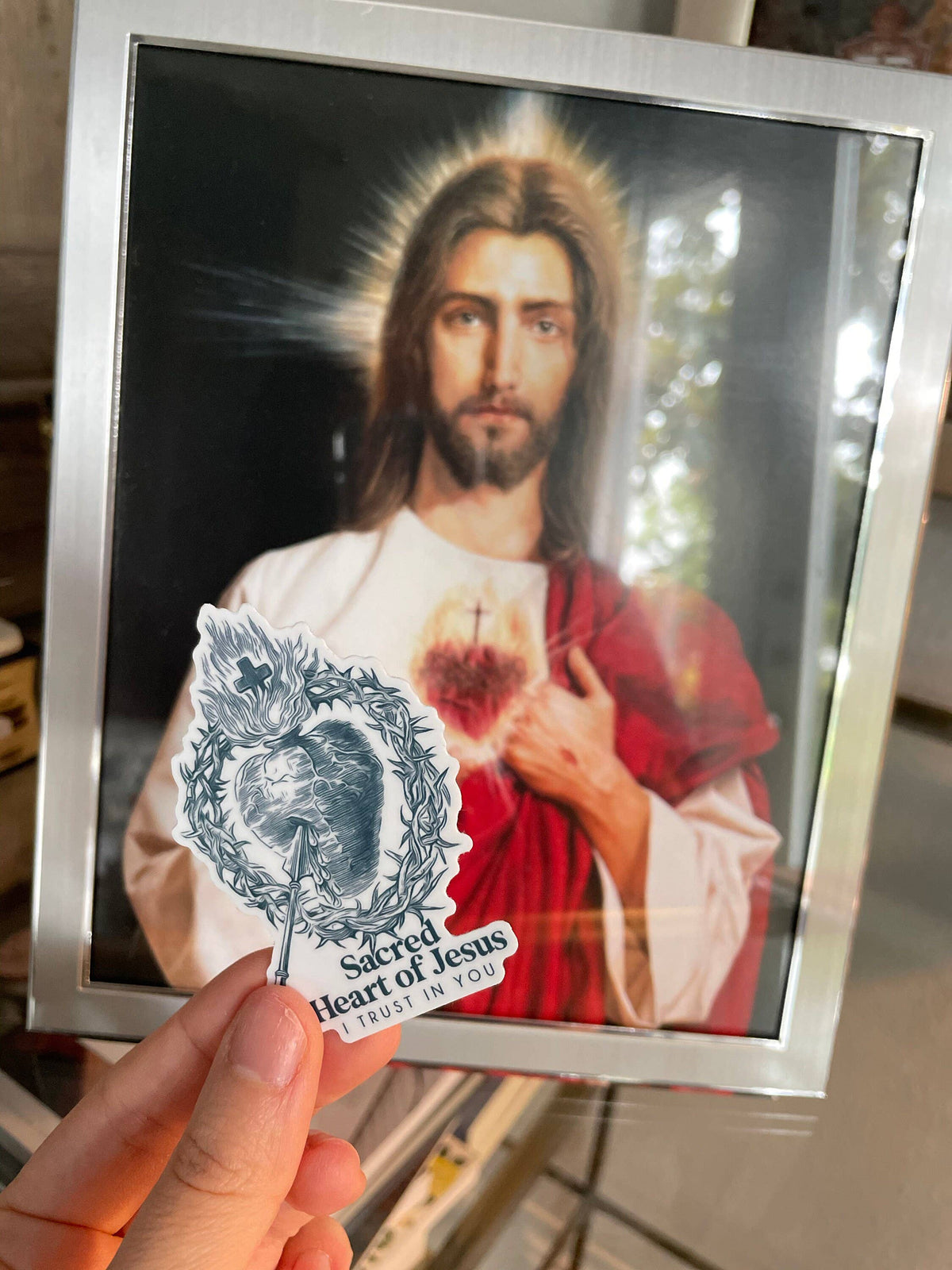 Card with a portrait of Jesus and 'Sacred Heart of Jesus' emblem held by a hand.