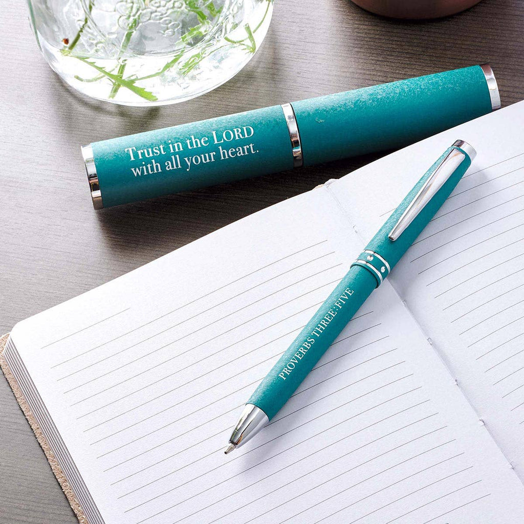 Teal pen and pen holder with motivational Bible quote on a notebook