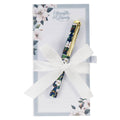 Pen with floral design and gold accents on a card with white ribbon