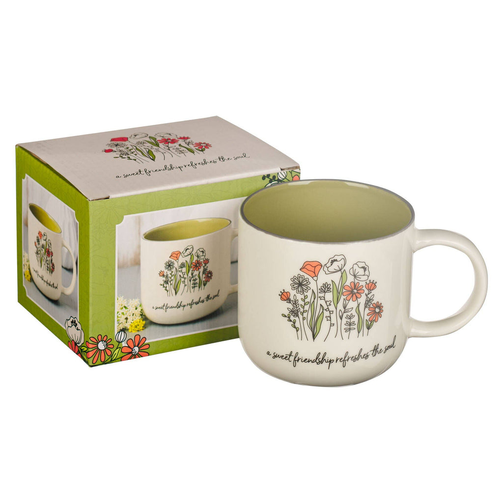 White mug with floral designs and text, displayed with packaging on a white background