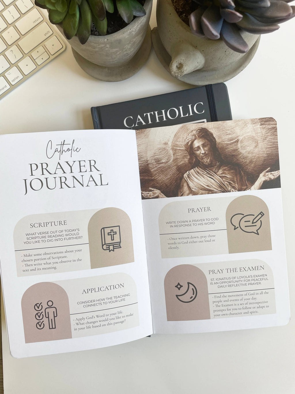 Catholic prayer journal on a desk with plants and a keyboard