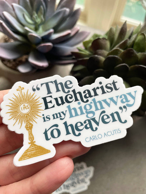 Sticker with religious text held by a hand, with plants in the background
