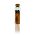 Glass bottle with cork lid containing matches on a white background