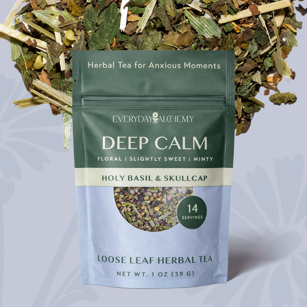A stand-up pouch of Everyday Alchemy Deep Calm herbal tea, shown in front of loose leafy tea pieces. The pouch is dark green on the upper half and pale blue on the lower half, with white text and a circular window displaying the loose tea blend.