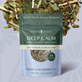 A stand-up pouch of Everyday Alchemy Deep Calm herbal tea, shown in front of loose leafy tea pieces. The pouch is dark green on the upper half and pale blue on the lower half, with white text and a circular window displaying the loose tea blend.
