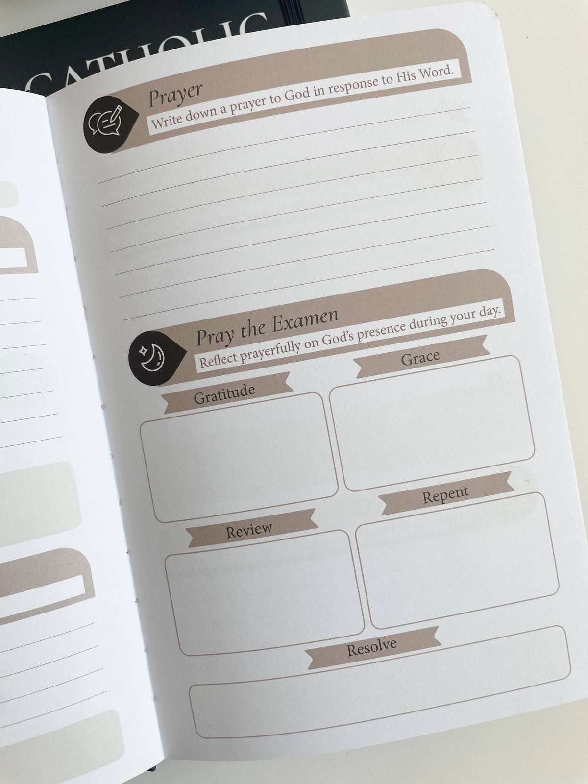 Prayer journal with lined pages and prompts for reflection on a white surface