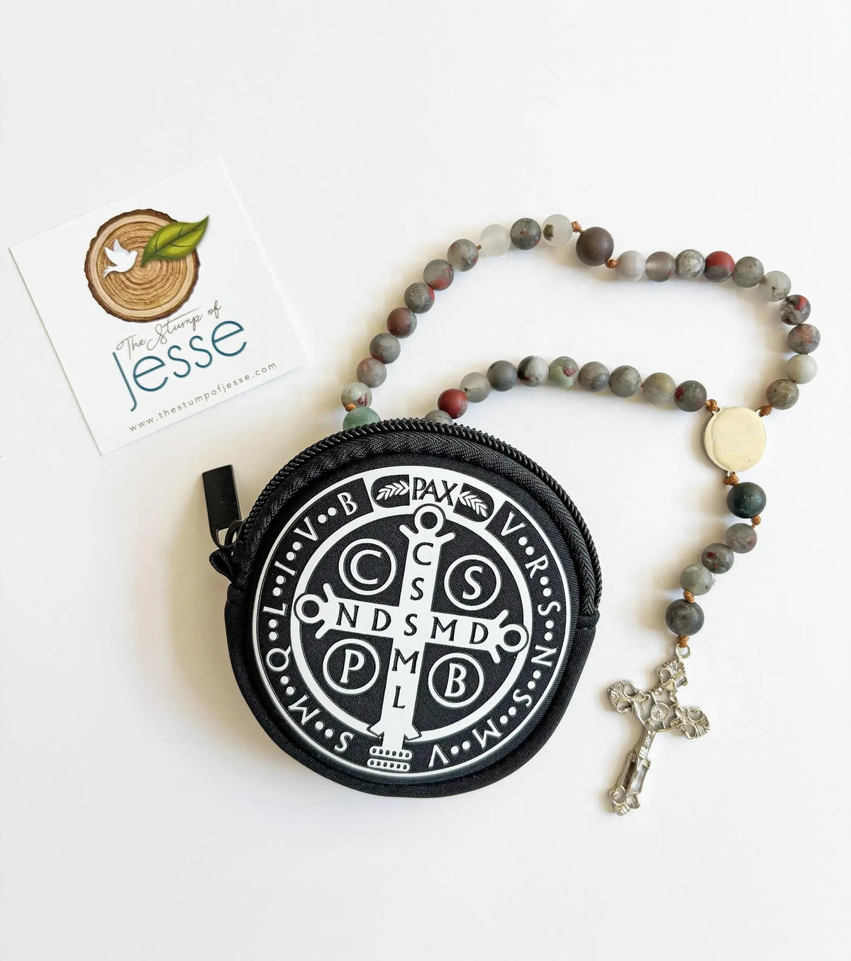 Round black St. Benedict Medal Rosary Pouch with white emblem and rosary on a white background
