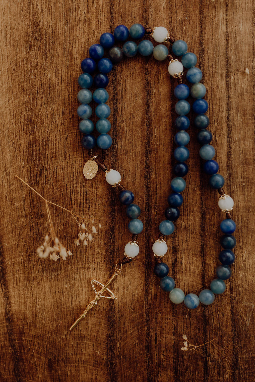 Blue beaded rosary with a cross pendant on a wooden surface