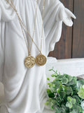Gold necklaces with circular pendants on a white statue background
